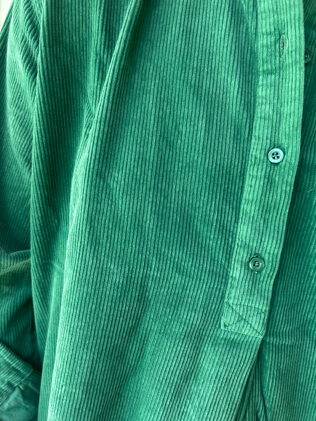 Close-up of a green corduroy shirt with buttons