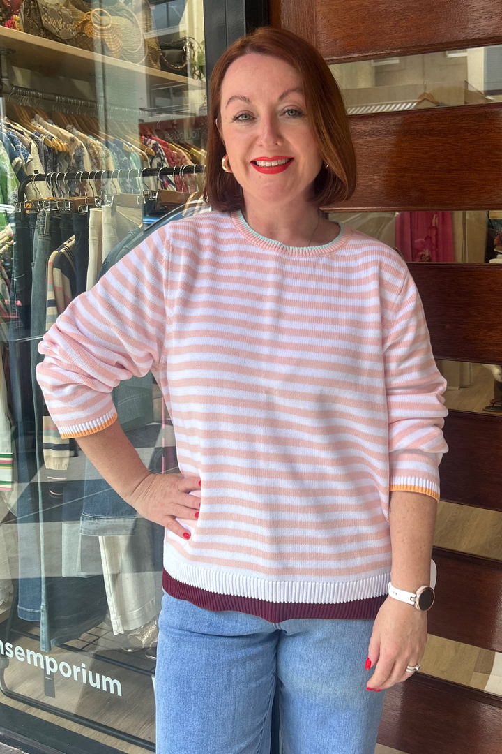 Woman standing in front of a store with a striped sweater and jeans