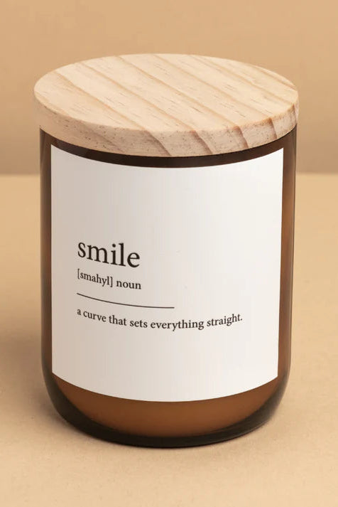 A candle jar with a wooden lid labeled 'smile' on a beige background.