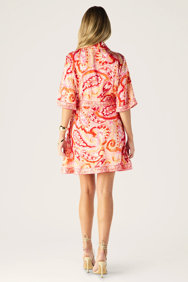 Woman wearing a red and orange patterned dress on a white background