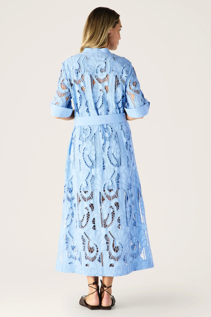 Woman wearing a light blue dress with lace details on a white background