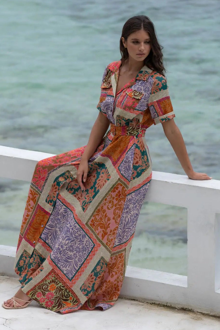 Woman in a colorful dress standing by a body of water