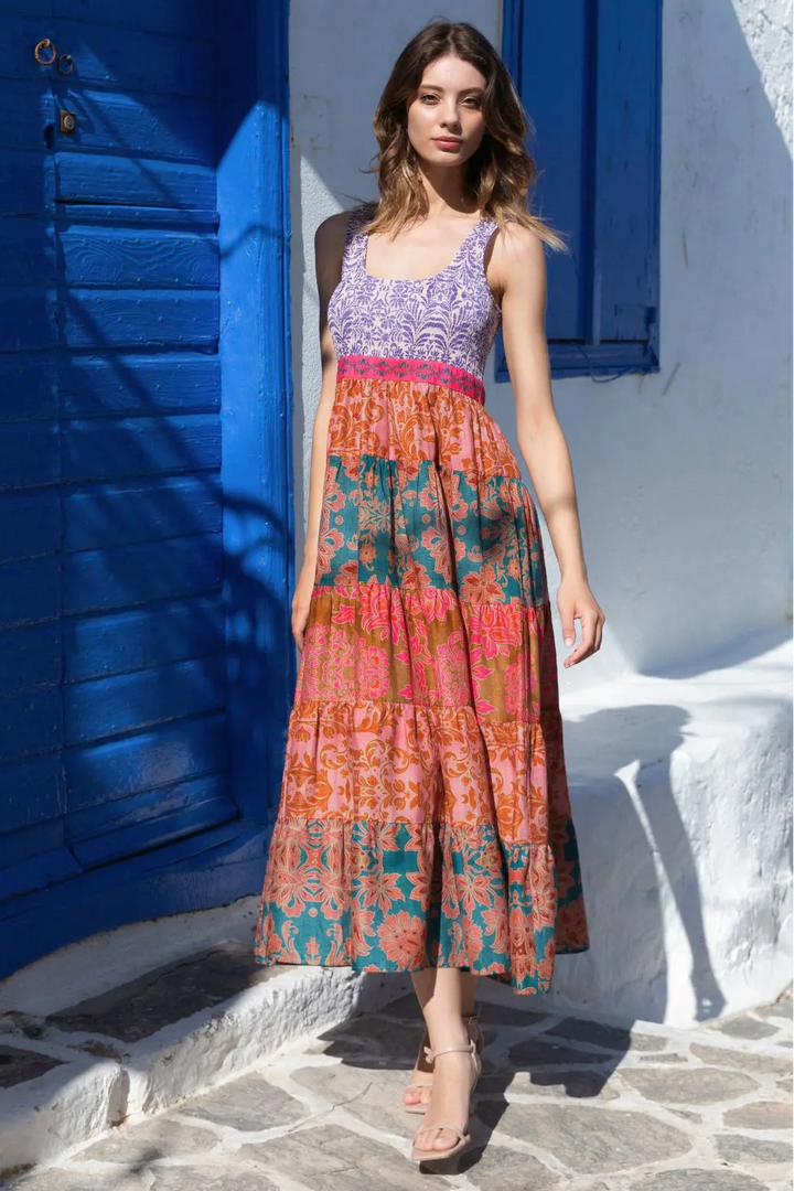 Woman in a colorful dress standing in front of a blue door and white wall.