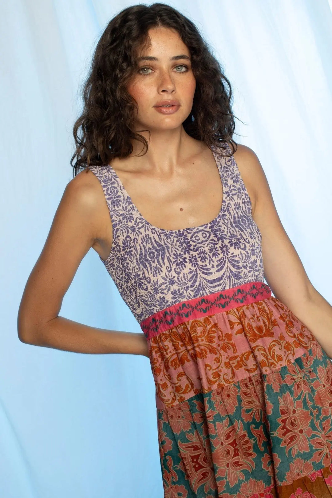 Woman wearing a patterned sleeveless top and skirt against a light blue background