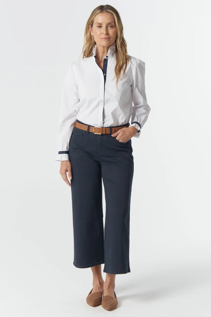 Woman wearing a white blouse and navy pants on a white background