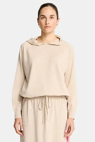 Woman wearing a beige outfit with a pink stripe on a white background