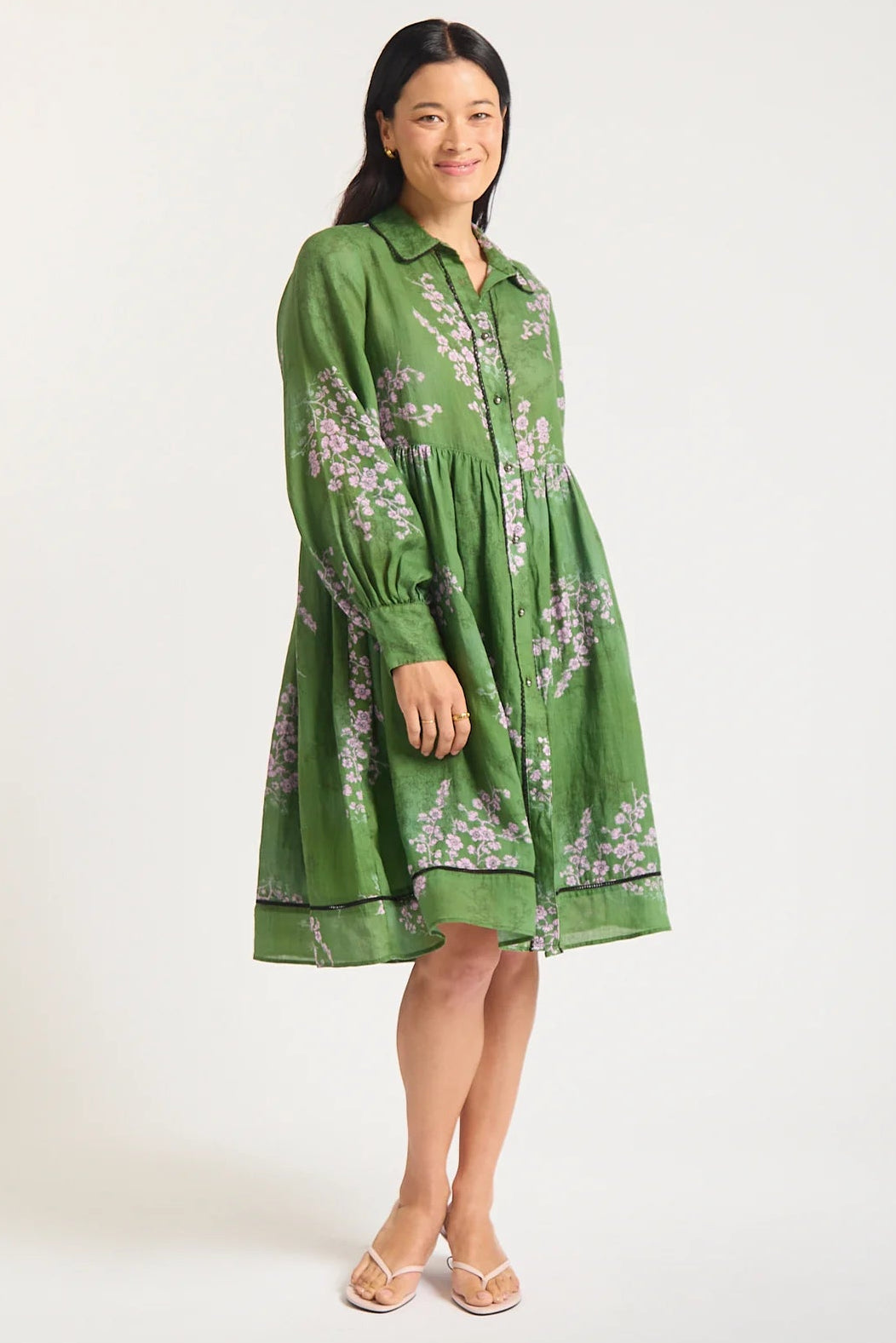 Woman wearing a green dress with floral pattern on a white background