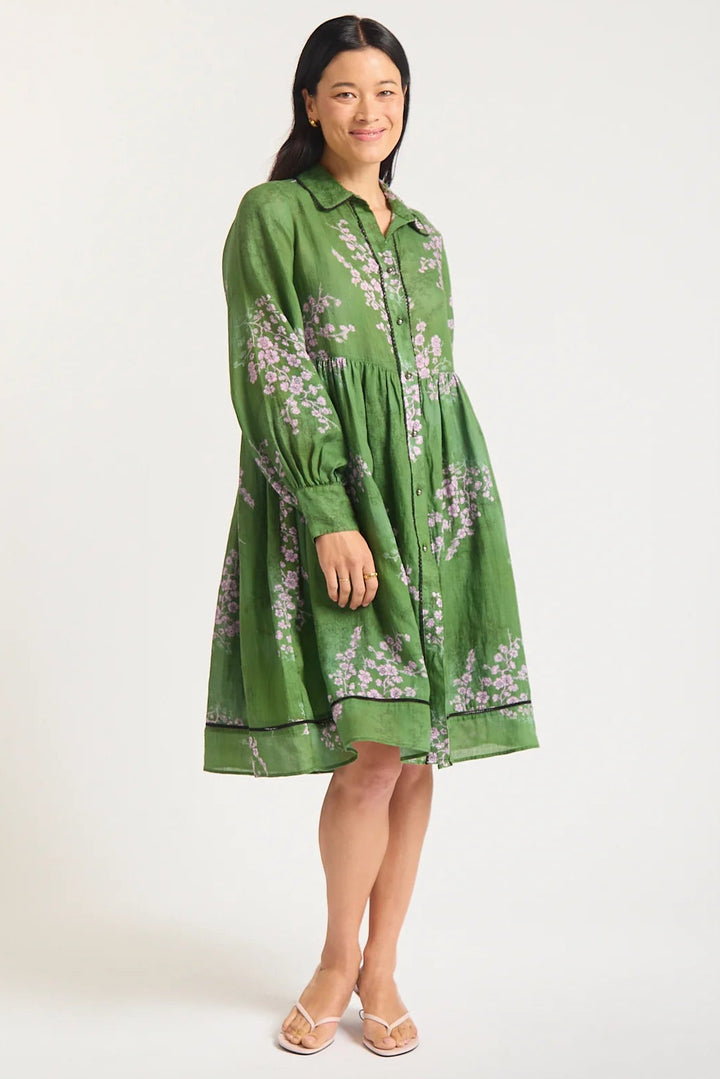 Woman wearing a green dress with floral pattern on a white background