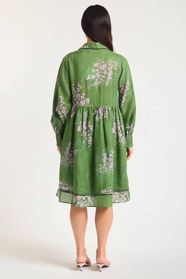 Woman wearing a green dress with floral patterns on a white background