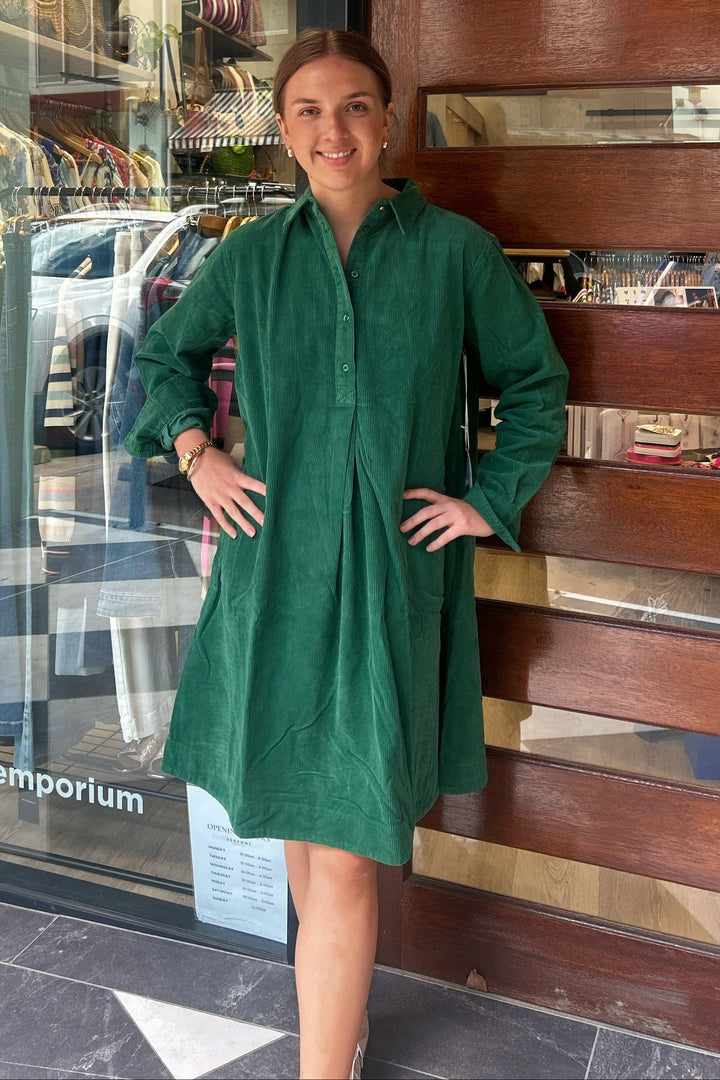 Woman in a green dress standing in front of a store entrance with 'SASONS' branding.