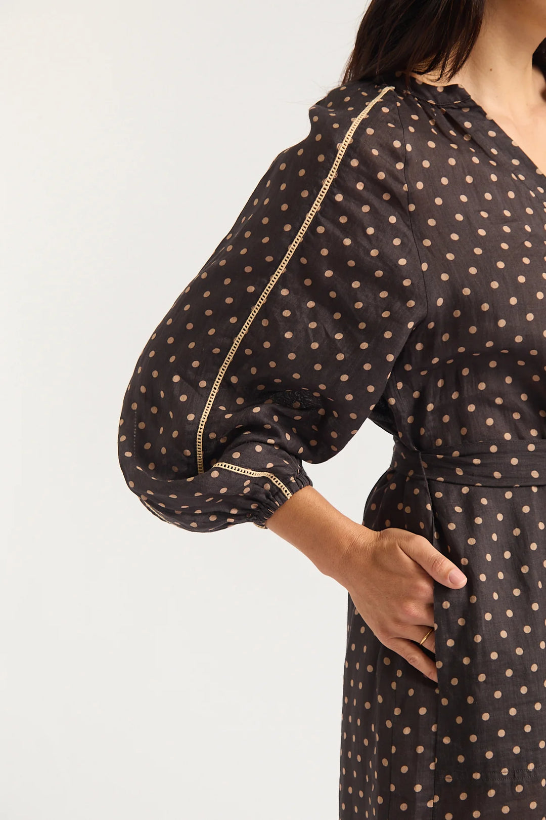 Woman wearing a black dress with gold polka dots on a white background