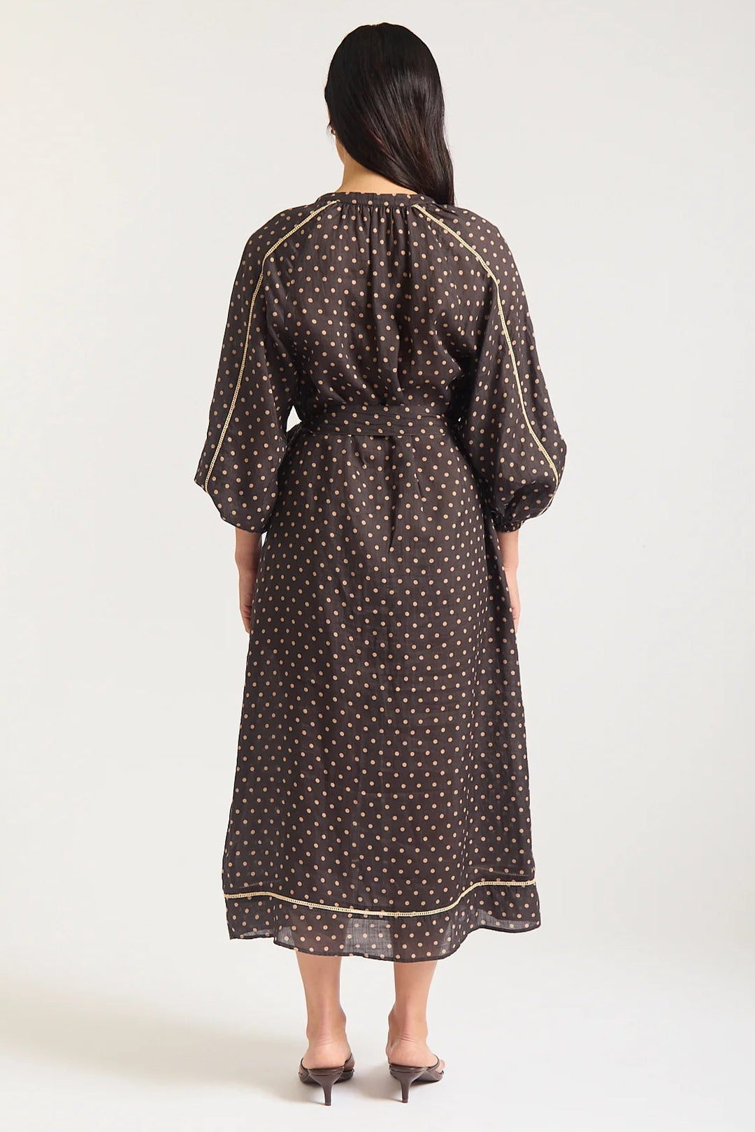 Woman wearing a black dress with white polka dots on a white background