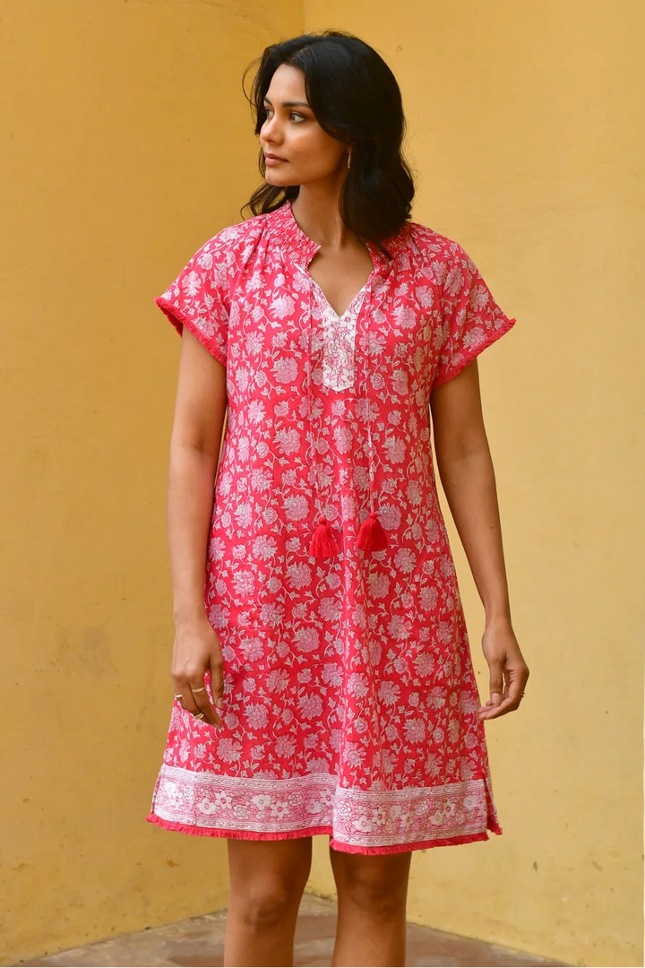 Woman wearing a red floral dress against a yellow wall