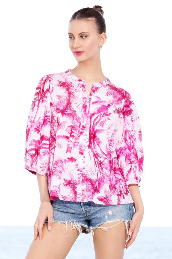 A model wearing a pink and white palm leaf patterned shirt with short sleeves and a round neckline.