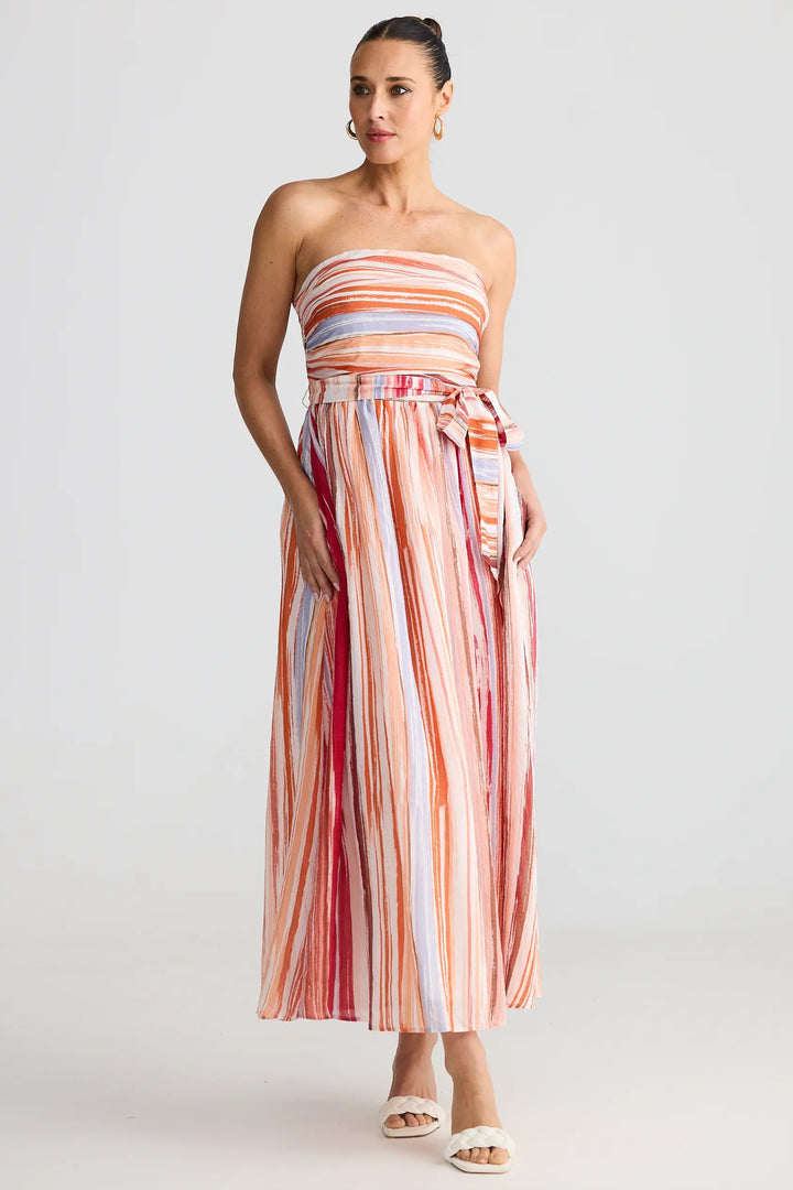Woman wearing a strapless, multicolored striped dress on a white background