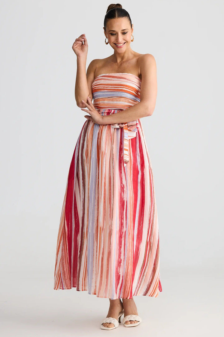 Woman wearing a strapless, long, multicolored striped dress on a white background