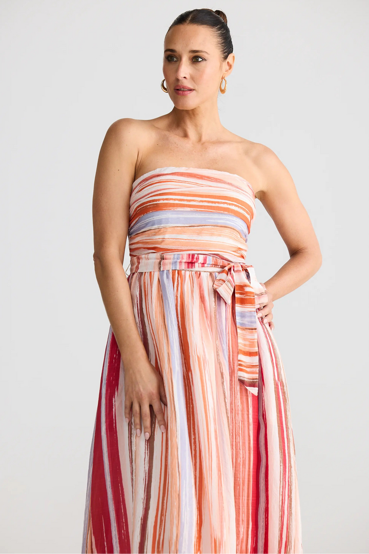 Woman wearing a strapless, multicolored dress against a plain background