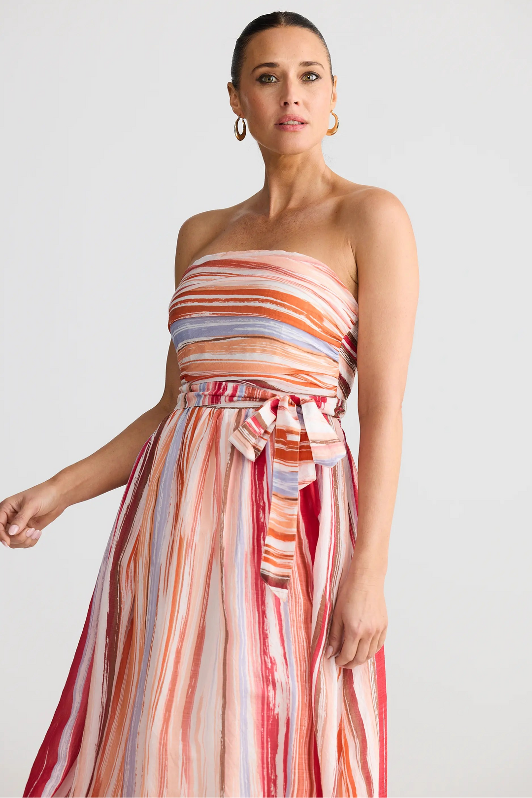 Woman wearing a strapless, multicolored dress against a plain background