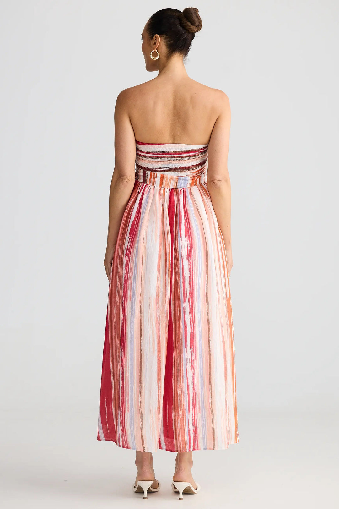 Woman wearing a strapless, long, red and white striped dress on a plain background