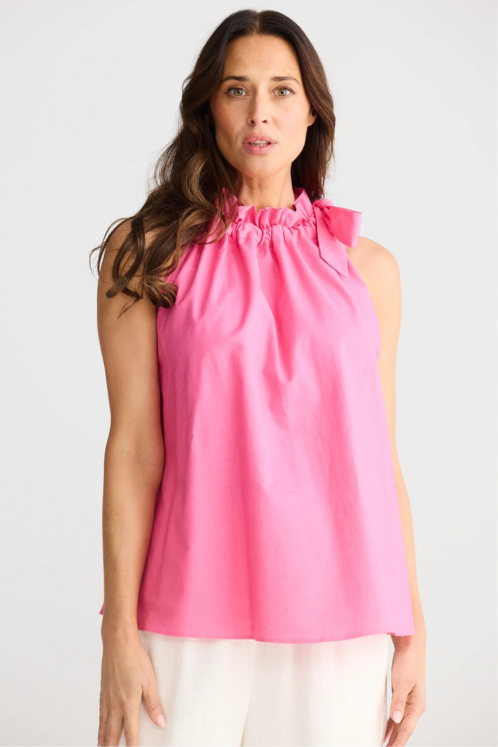 Woman wearing a pink sleeveless top against a white background