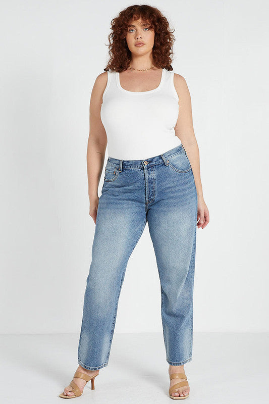 A female model wearing a white tank top and mid blue slim mum jeans with a straight leg cut.