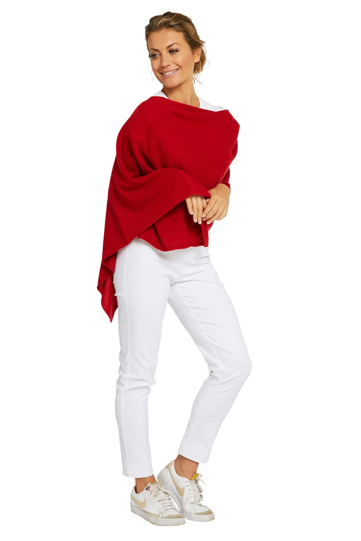 Woman wearing a red poncho and white pants on a white background