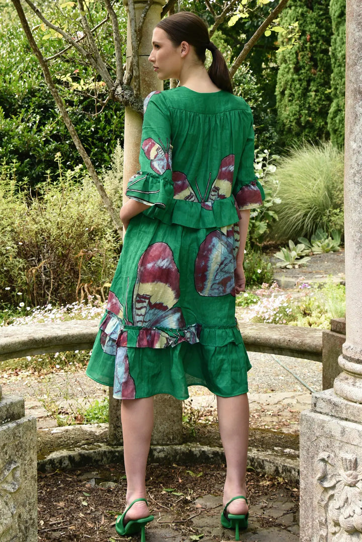 Woman wearing a green dress with colorful patterns in a garden setting