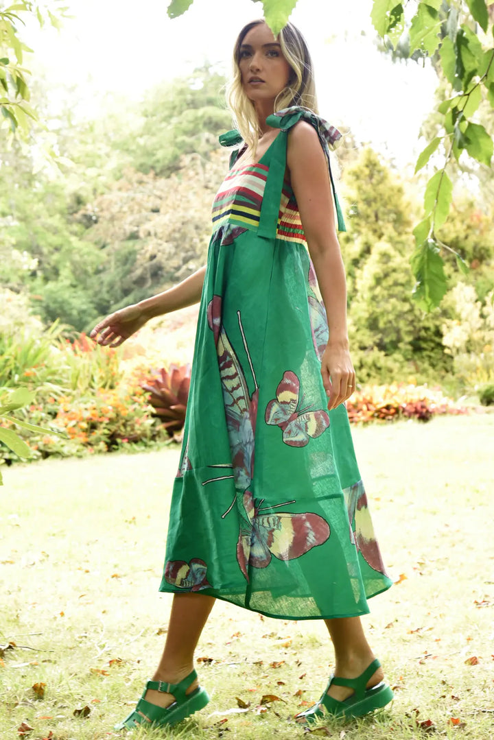 Woman wearing a green dress with butterfly patterns in a garden setting