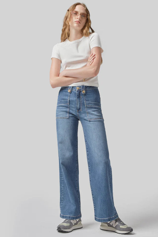 Woman wearing a white t-shirt and blue jeans on a light gray background