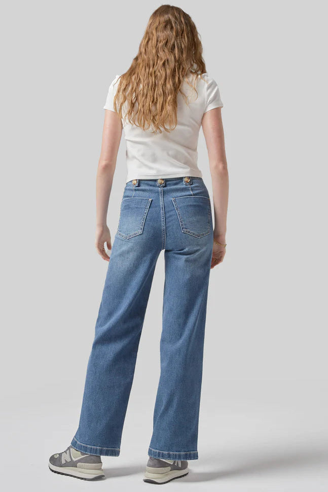Person wearing blue jeans and a white shirt on a plain background