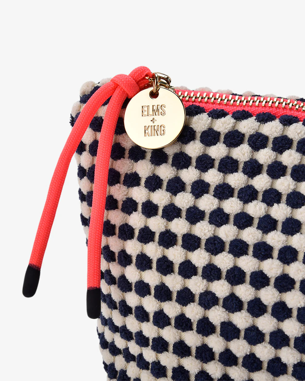 Polka dot pouch with pink strap and gold tag on a white background. Elms & King Napili Large Navy White