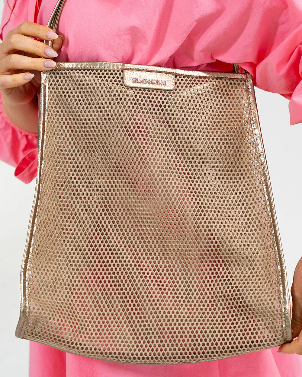 Gold mesh handbag held by a person wearing a pink outfit