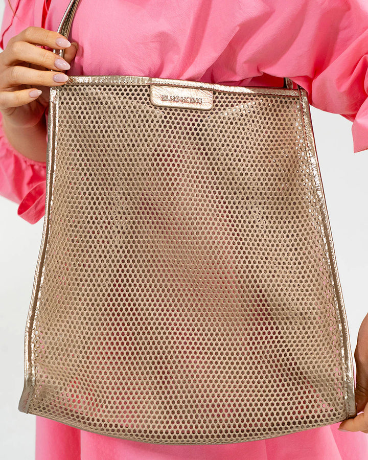 Gold mesh handbag held by a person wearing a pink outfit