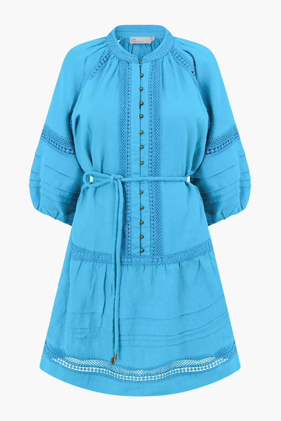 A bright turquoise blue tunic dress with three-quarter sleeves, a matching waist tie, and decorative embroidered details, shown against a plain light gray background.