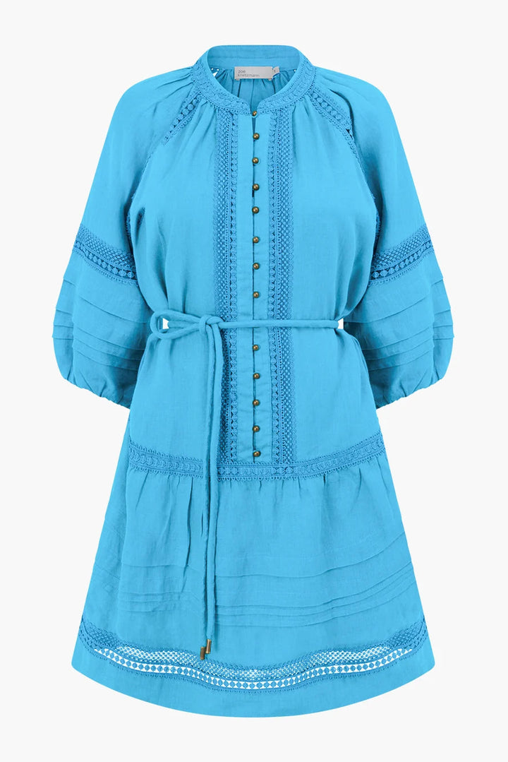 A bright turquoise blue tunic dress with three-quarter sleeves, a matching waist tie, and decorative embroidered details, shown against a plain light gray background.
