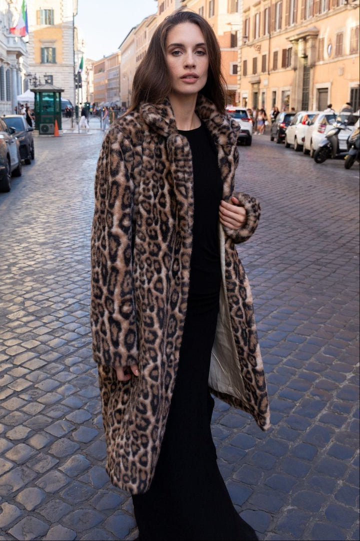 Woman in a leopard print coat walking on a city street.