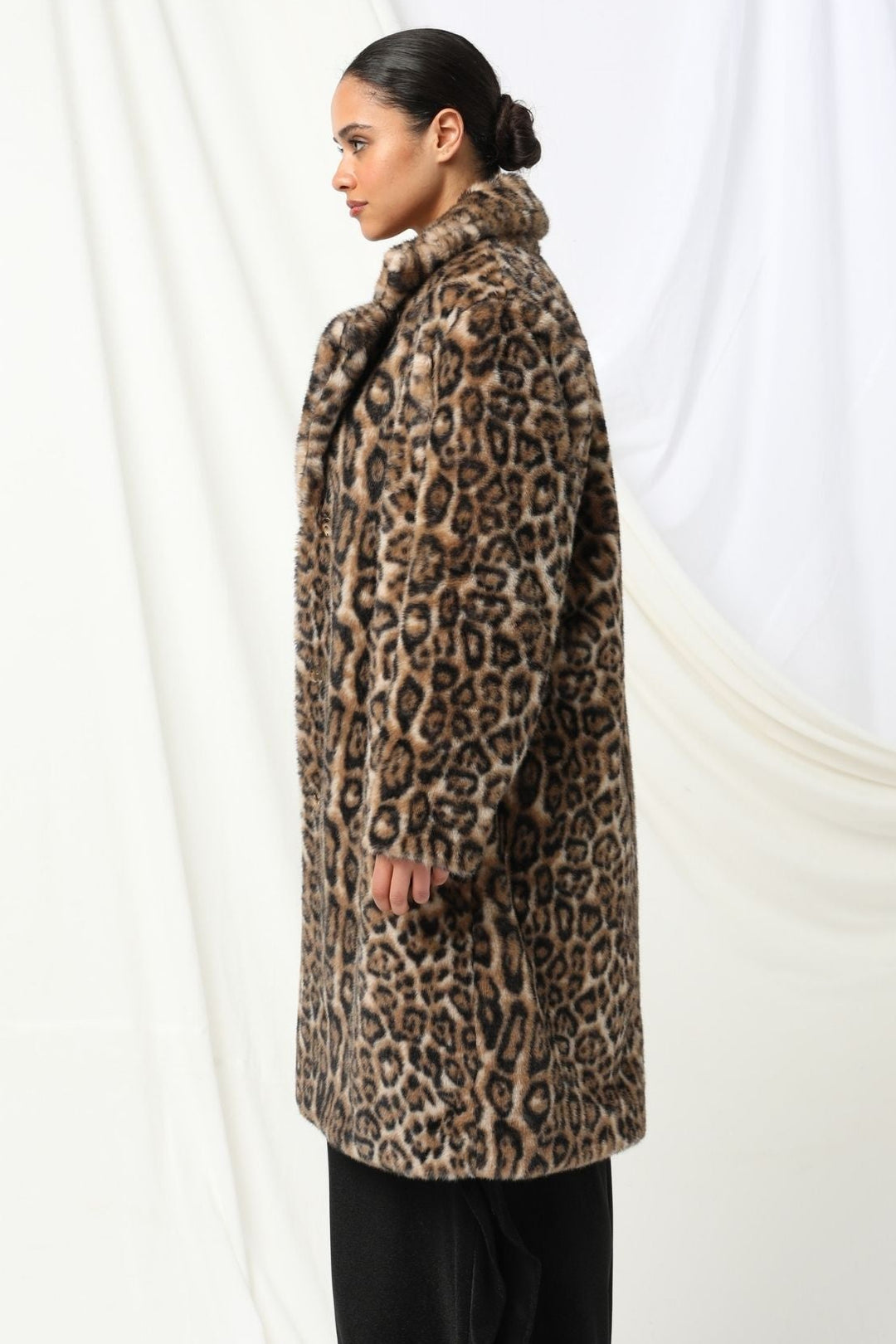 Woman wearing a leopard print coat against a white background