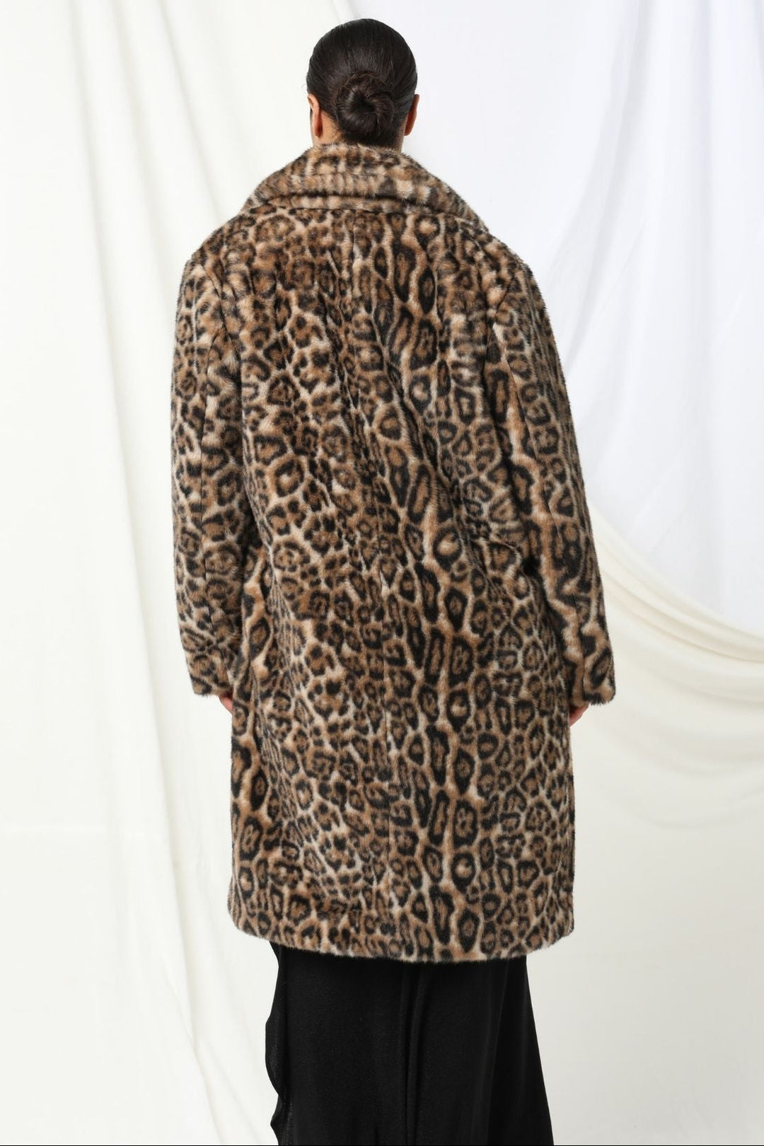 Person wearing a leopard print coat against a white background