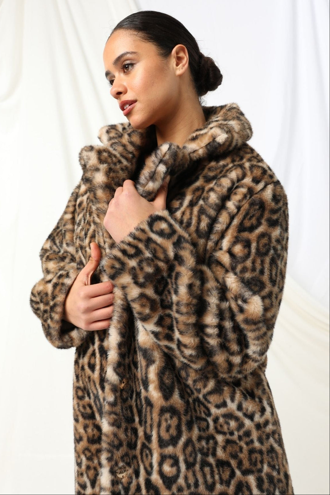 Woman wearing a leopard print coat against a white background
