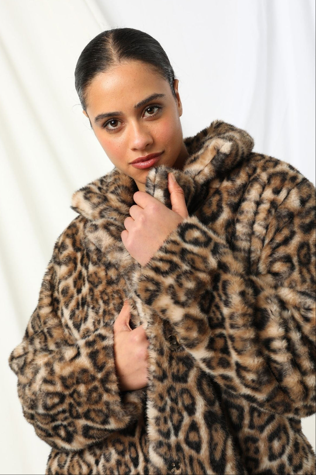 Woman wearing a leopard print coat against a white background