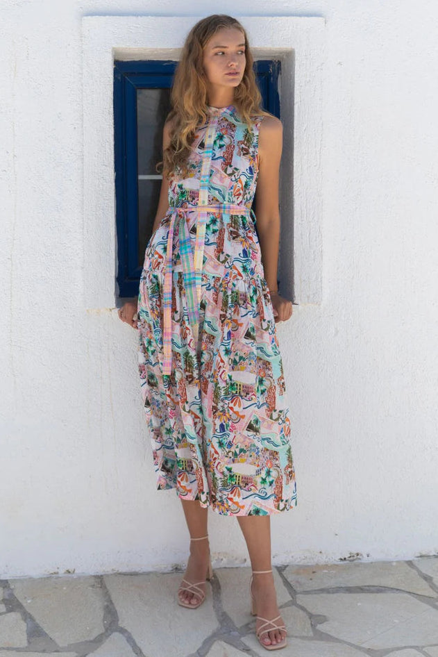 Woman in a floral dress standing in front of a white wall with a blue door.