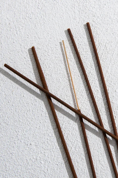 Five incense sticks on a textured white surface