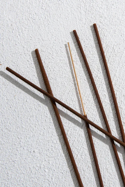 Five incense sticks on a textured white surface