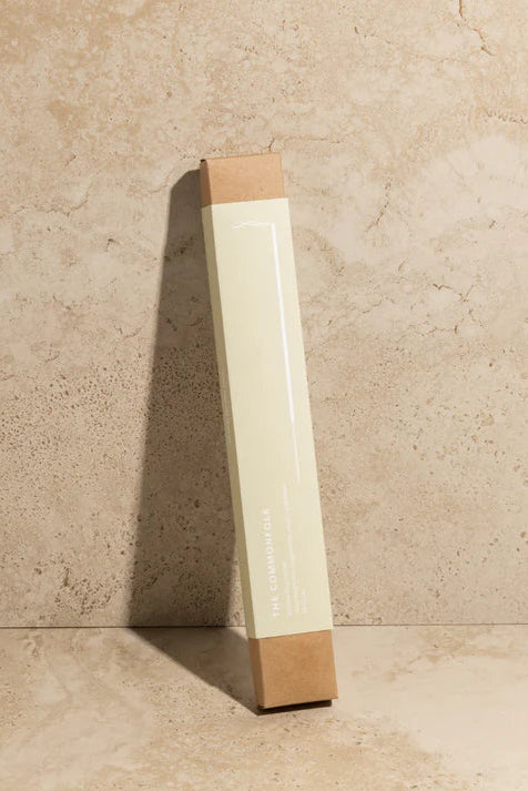 Tall rectangular object with a brown base and white top against a beige stone wall.