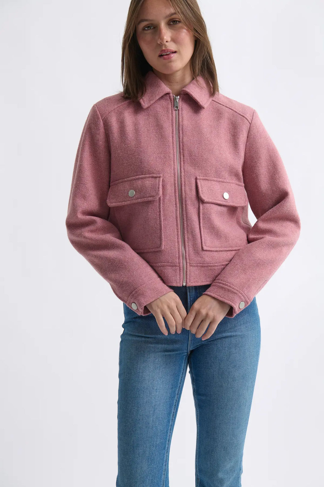 Person wearing a pink jacket and blue jeans on a white background