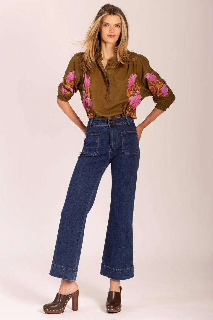 Woman wearing a brown floral blouse and blue jeans on a white background