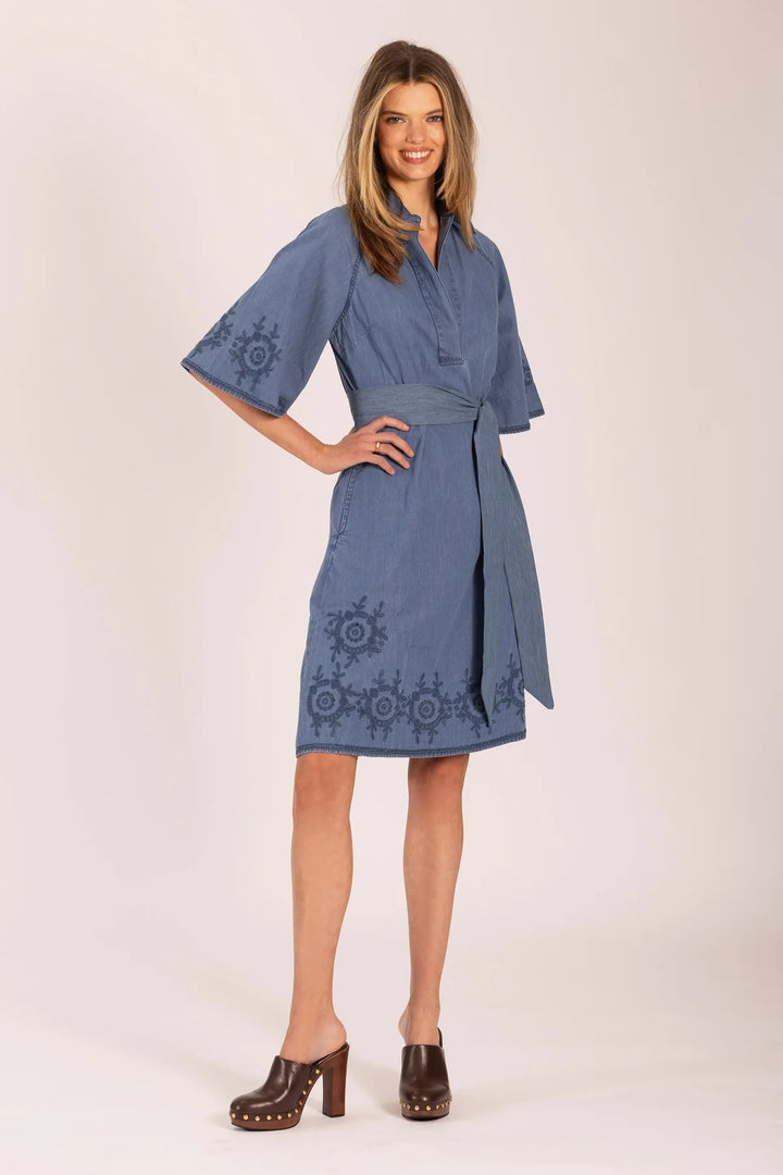 Woman wearing a blue dress with embroidery on a white background