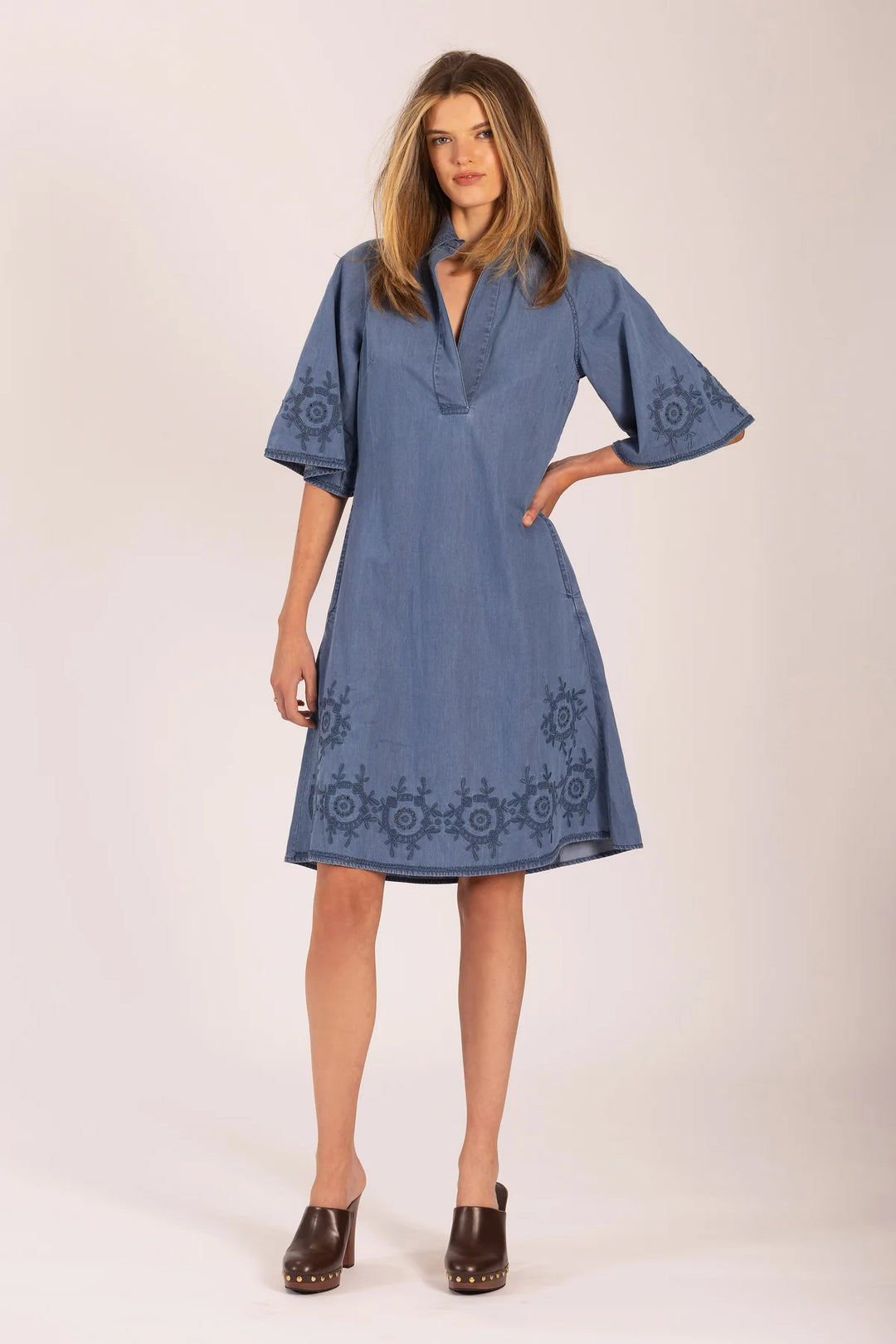 Woman wearing a blue dress with embroidery on a white background