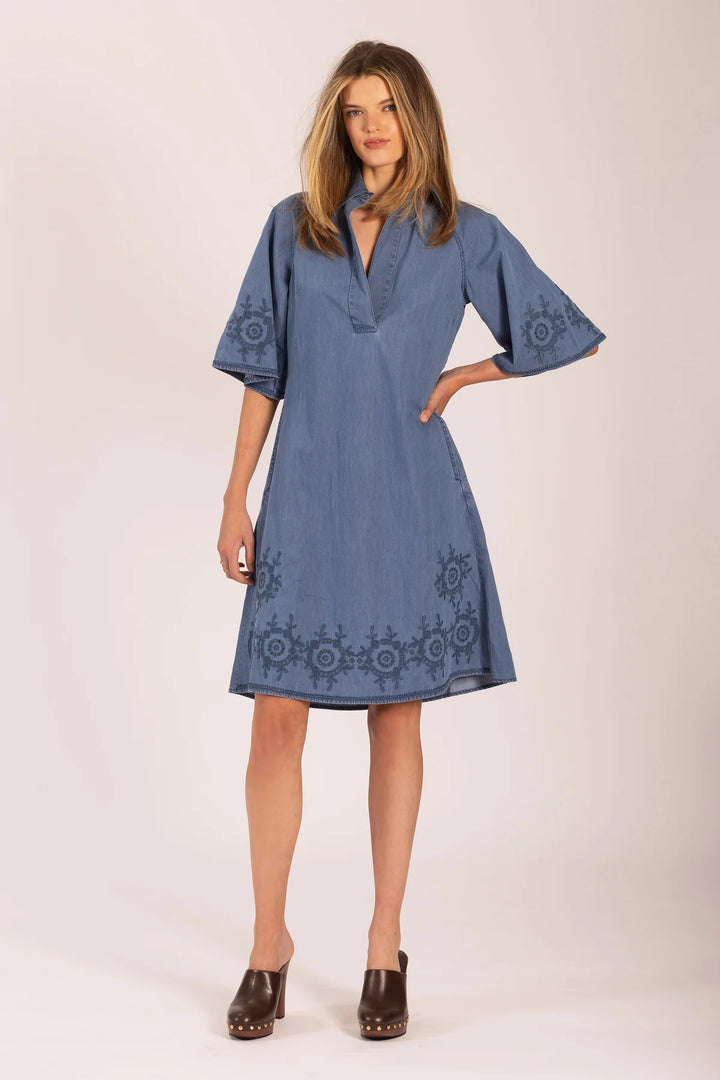 Woman wearing a blue dress with embroidery on a white background