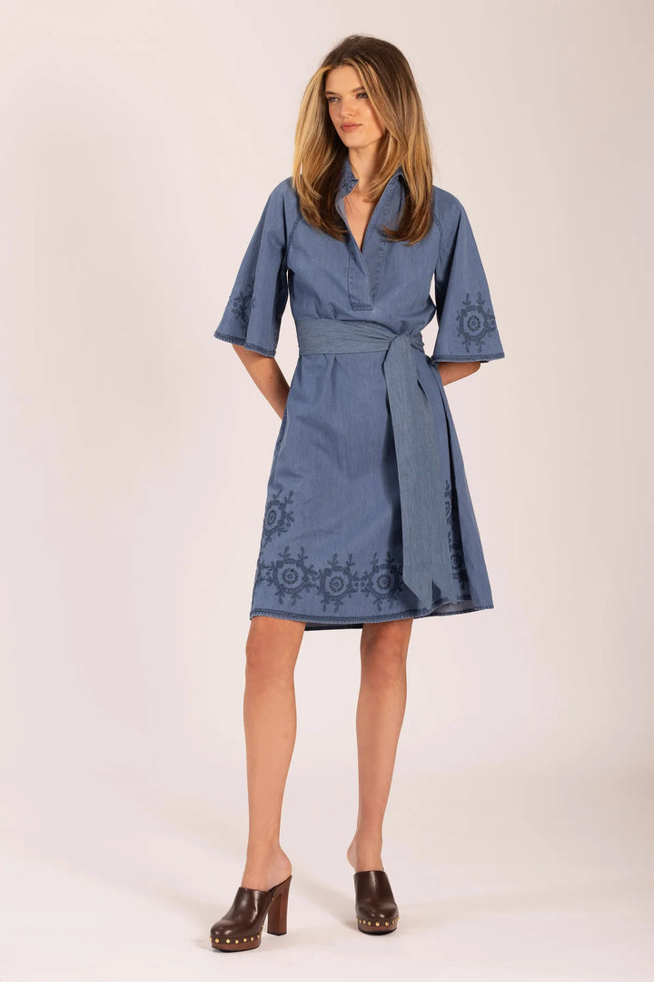 Woman wearing a blue dress with embroidery on a white background